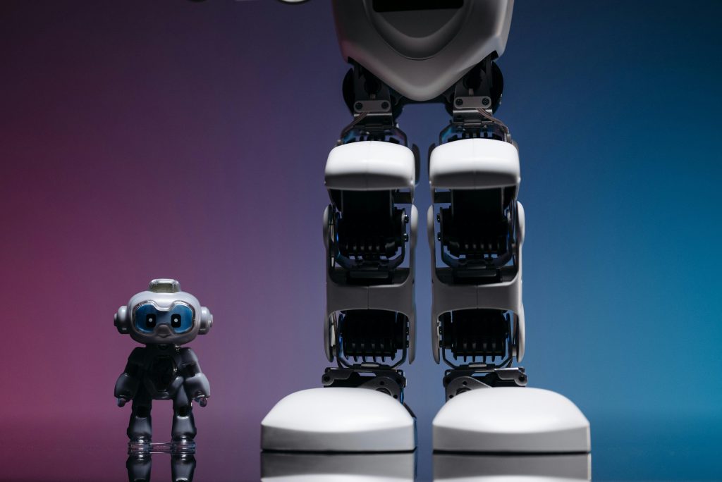 A large robot stands beside a small toy robot with colorful studio lighting, showcasing technology innovation.